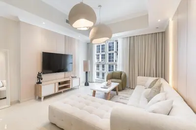 a living room with a white couch and a television at Amal أمل Cozy City Apt 3BD with balconies, 1 min walk to Dubai Mall- Dar Samita Holiday Homes in Dubai