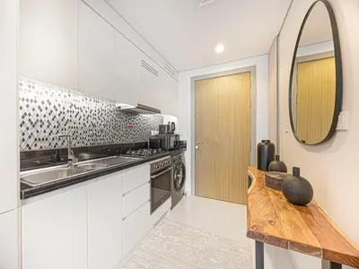 a kitchen with white cabinets and a sink and a mirror at Livin' Holiday - Studio - Cozy Flat in Business Bay in Dubai