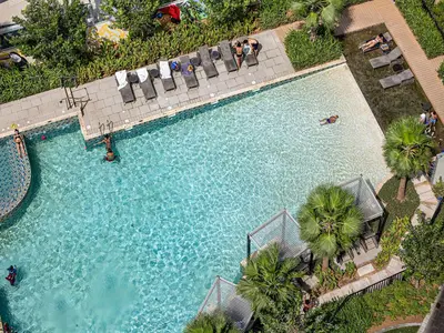 an overhead view of a swimming pool with palm trees at Livin' Holiday - Studio - Cozy Flat in Business Bay in Dubai