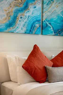 two red pillows on a white couch under a painting at Livin' Holiday - Studio - Cozy Flat in Business Bay in Dubai