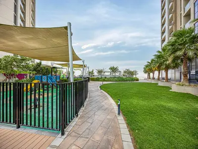 a park with a fence and grass and palm trees at Livin' Holiday - Studio - Cozy Flat in Business Bay in Dubai