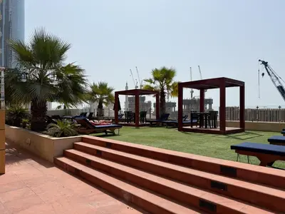 a park with benches and picnic tables and palm trees at The Smart Concierge - Elite Residence in Dubai
