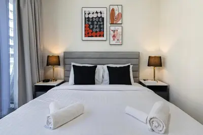 a bedroom with a large white bed with two lamps at Upscale 1 Bedroom Apartment - Azizi Riviera 27 - Allsopp & Allsopp in Dubai