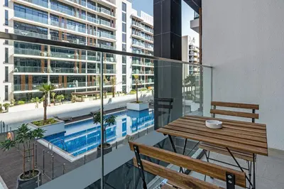 a balcony with a table and bench and a swimming pool at Upscale 1 Bedroom Apartment - Azizi Riviera 27 - Allsopp & Allsopp in Dubai