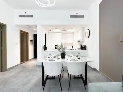 a white dining room with a table and chairs at Golden Glow Getaway 1BR in JVC in Dubai