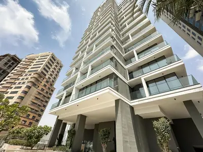 a tall building with two tall buildings at Golden Glow Getaway 1BR in JVC in Dubai