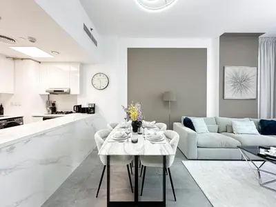 a white living room with a table and a couch at Golden Glow Getaway 1BR in JVC in Dubai