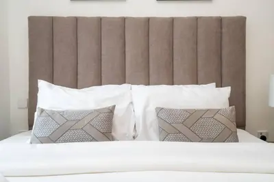 a bed with white pillows and a brown headboard at Elegant 1 Bed Creek Beach Stay with Beach Access in Dubai