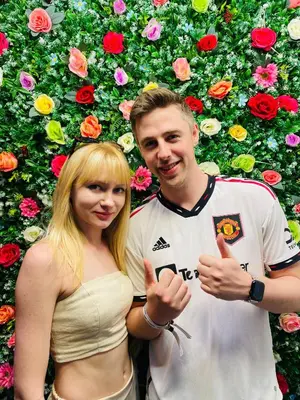 a man and a woman standing in front of a wall of flowers at dreams stay in Dubai