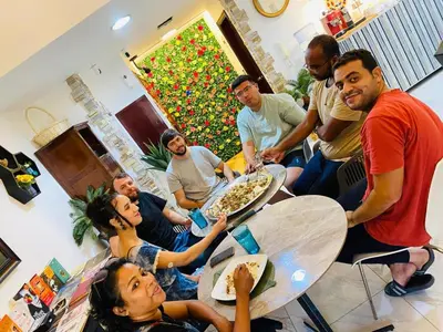 a group of people sitting around a table eating pizza at dreams stay in Dubai