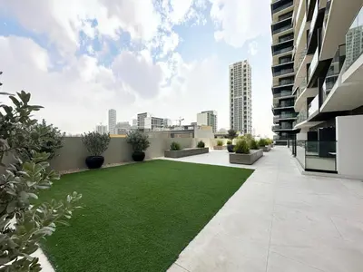 a courtyard with a green lawn in a building at Modern 1BR Haven in Prime JVC Spot in Dubai