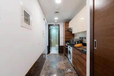a kitchen with white walls and a hallway with a dishwasher at Cozy - Accessible to Tram - Convenient in Dubai