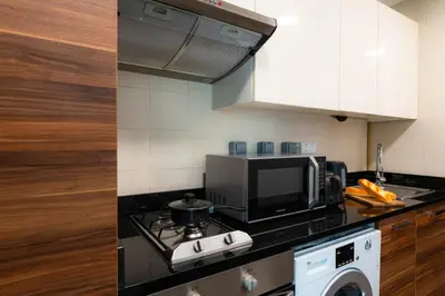 a kitchen with a stove top oven next to a microwave at Cozy - Accessible to Tram - Convenient in Dubai