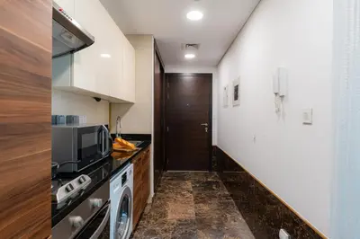 a kitchen with a washer and dryer and a door at Cozy - Accessible to Tram - Convenient in Dubai