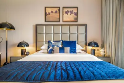 a bedroom with a large blue bed with two lamps at GuestReady - City Nest | Balcony | Majestine Tower in Dubai