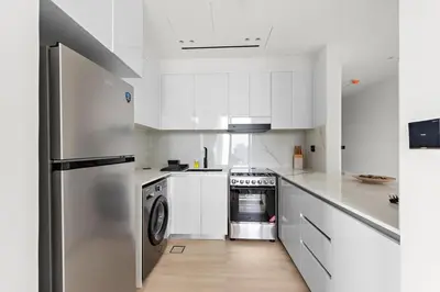 a kitchen with white cabinets and a stainless steel refrigerator at Cozy 1BR Apartment with Pool & Parking JVC Dubai in Dubai