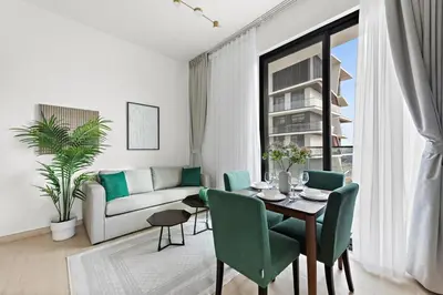 a living room with a table and green chairs at Cozy 1BR Apartment with Pool & Parking JVC Dubai in Dubai