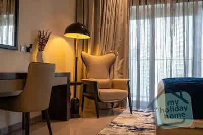 a hotel room with two chairs and a desk and a bed at Burj Khalifa View - Cozy 1BR - Pool - Gym - Spa in Dubai