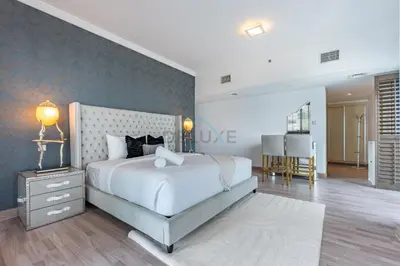 a bedroom with a large white bed and a dining room at Walking Distance to Bluewaters Island, with The Walk JBR right at your Door and Private Beach Access, Al Bateen Residences, JBR by Deluxe Holiday Homes in Dubai