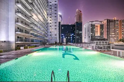 a large swimming pool in a city at night at Heart of Downtown - Dubai Mall & Burj next door in Dubai