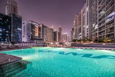 a large swimming pool in a city at night at Heart of Downtown - Dubai Mall & Burj next door in Dubai