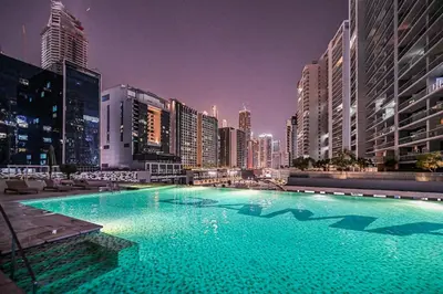 a large swimming pool in a city at night at Live in the Center - Walk to Dubai Icons in Dubai