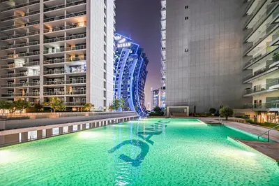a swimming pool in the middle of a city at night at Live in the Center - Walk to Dubai Icons in Dubai