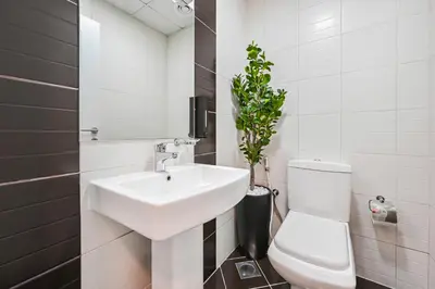 a bathroom with a sink and a toilet and a plant at Elegant 3-Bedroom Haven - Panoramic Marina Views in Dubai