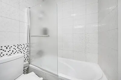 a white bathroom with a shower and a toilet at Elegant 3-Bedroom Haven - Panoramic Marina Views in Dubai