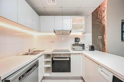 a white kitchen with a sink and a microwave at Elegant 3-Bedroom Haven - Panoramic Marina Views in Dubai