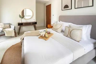 a bedroom with a large white bed with a table at Frank Porter - Dunya Tower, Downtown in Dubai