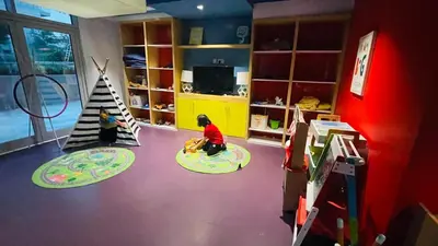 two children playing in a room with a toy house at DAMAC Majestine Studio with Pool, Spa and Gym Near Bus & DubaiMall in Dubai