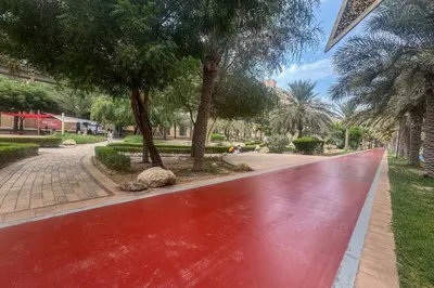 a red walkway in a park with trees at Elegant Palm Living Upgraded Golden Mile 1 Bed in Dubai
