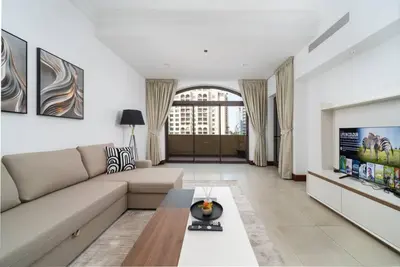 a living room with a couch and a tv at Elegant Palm Living Upgraded Golden Mile 1 Bed in Dubai