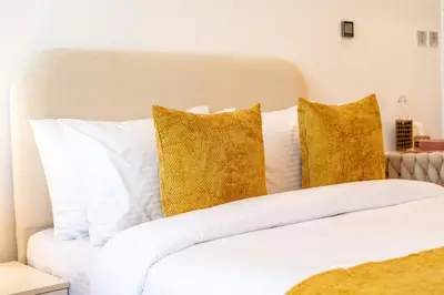 a white bed with white pillows and yellow pillows at Nice New Studio 2 Double Beds In Downtown, Free Parking in Dubai