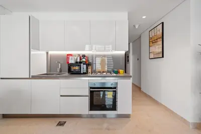 a kitchen with white cabinets and a stove at Nice New Studio 2 Double Beds In Downtown, Free Parking in Dubai