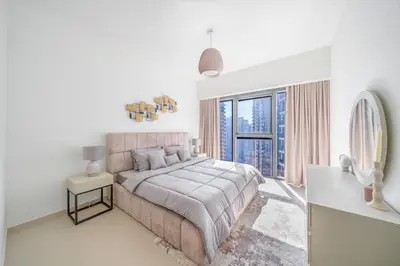 a white bedroom with a large bed and a window at Act tower 2BR, near burj khalifa in Dubai