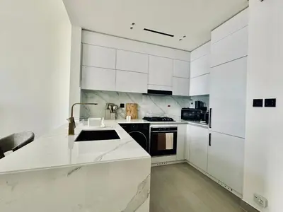 a white kitchen with white cabinets and a sink at Soft Toned 1BR Retreat with Pool, Gym and Parking! in Dubai