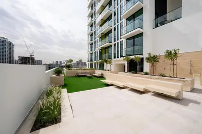 an apartment patio with benches and a lawn at Soft Toned 1BR Retreat with Pool, Gym and Parking! in Dubai