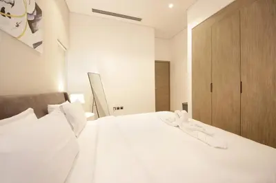 a bedroom with a white bed and a wooden cabinet at The Sterling By OMNIYAT Near To Dubai Mall in Dubai