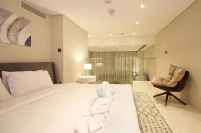 a bedroom with a large bed and a chair at The Sterling By OMNIYAT Near To Dubai Mall in Dubai