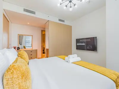 a bedroom with a white bed with a tv on the wall at 1BR at Vida -Steps from Dubai Mall & Burj Khalifa in Dubai