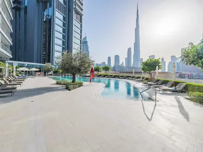 a person standing next to a swimming pool in a city at 1BR at Vida -Steps from Dubai Mall & Burj Khalifa in Dubai