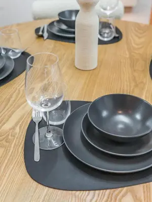 a table with black plates and glasses on a wooden table at 1BR at Vida -Steps from Dubai Mall & Burj Khalifa in Dubai