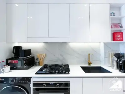 a kitchen with white cabinets and a stove top oven at JVC Retreat with Pool & Balcony in Dubai