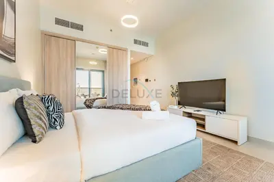 a bedroom with a large white bed and a flat screen tv at Steps from Dubai Hills Park, Walk to Dubai Hills Mall, 15-Minute Drive to Burj Khalifa and Dubai Mall, Sway Residences, Dubai Hills by Deluxe Holiday Homes in Dubai