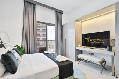 a bedroom with a large bed and a tv at Posh Studio in MBR by Deleguest in Dubai