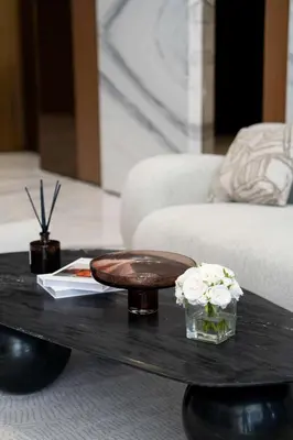 a coffee table with a plate and flowers on it at Lavish Studio Apt in Binghatti Azure - Pool & Gym in Dubai