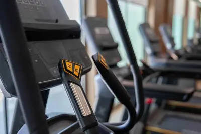 a row of treadmills in a gym with a phone at Lavish Studio Apt in Binghatti Azure - Pool & Gym in Dubai