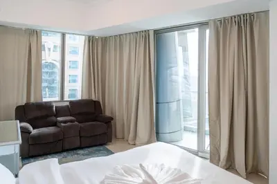 a living room with a couch and a large window at Luxury 2 BHK in Ocean Heights at Dubai Marina Living with Stunning Views in Dubai